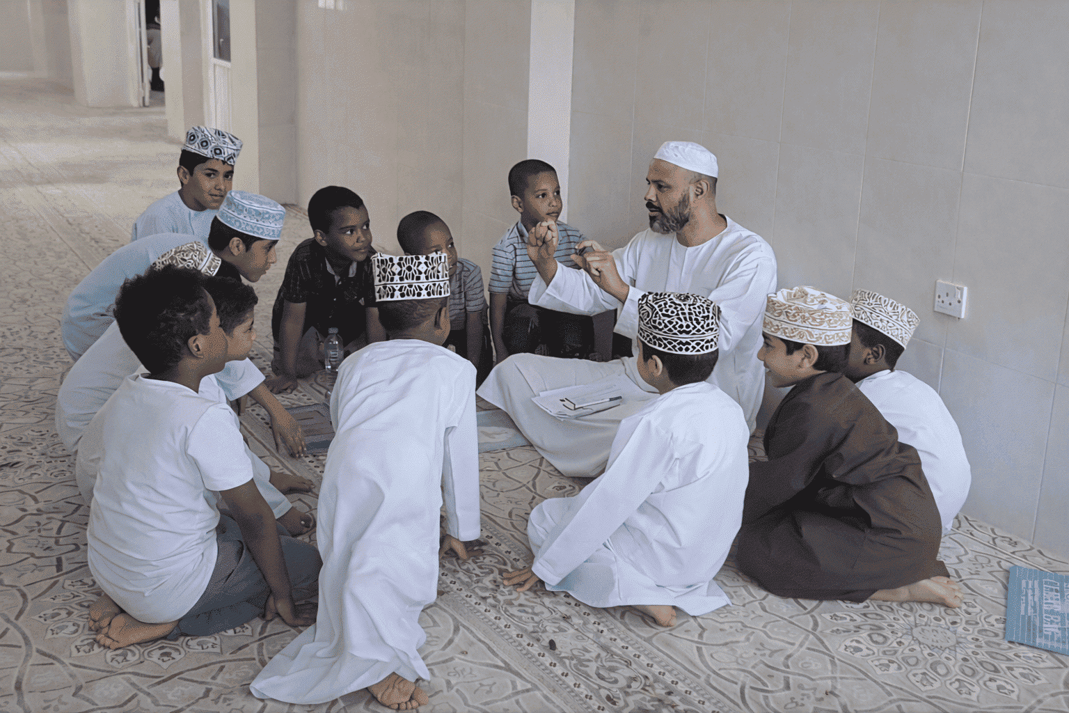 A tutor teaching a circle of young students the Qur'an in person